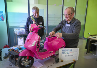 Electrical repairers from Maidstone Repair Cafe fixing a child's pink mini electric scooter